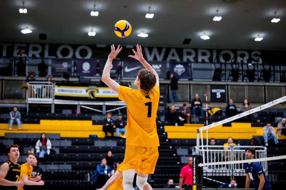 A men's volleyball player sets up a spike on the court.