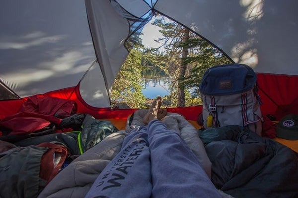 A photo snapped from inside a tent framing a desolate wilderness lake.
