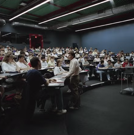 Professor Larry Smith converses with students in a lecture hall in the early 90s.