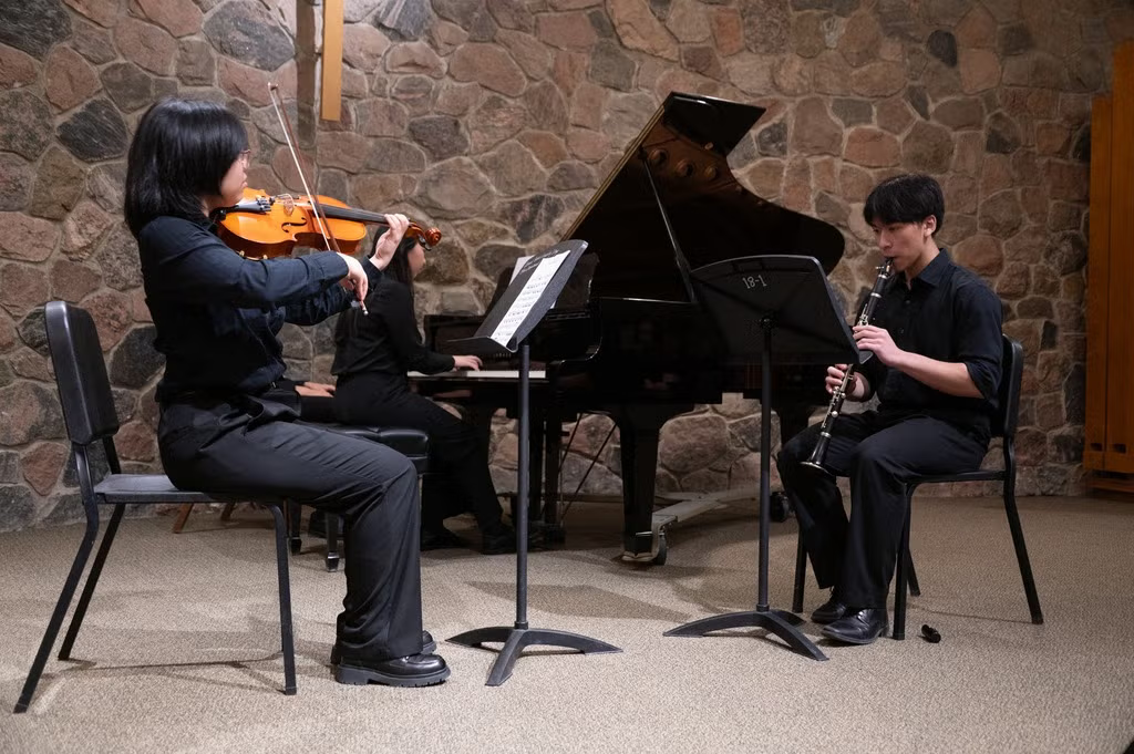 A musical trio - violinist, pianist, and clarinetist.