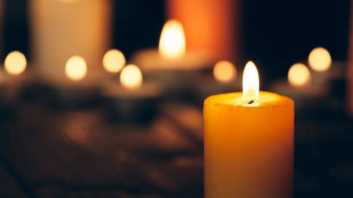 Candles flicker in the darkness.