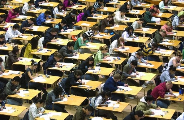 Students write exams at wooden tables in the PAC.