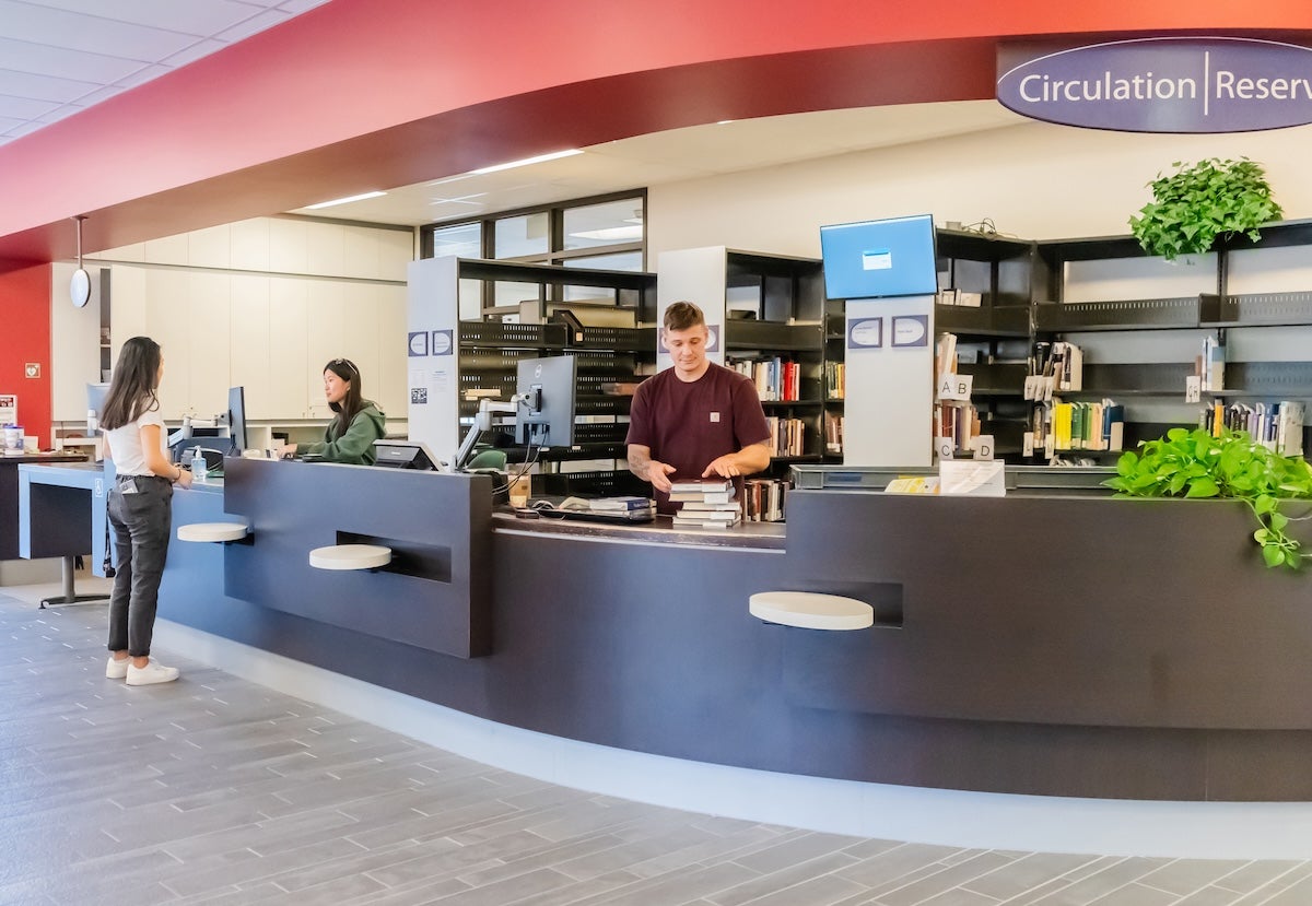 Employees and patron at the circulation desk.
