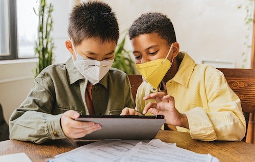 Two kids play together on a tablet device.