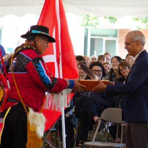 Myeengun Henry gives a gift to President Vivek Goel at the ceremony.