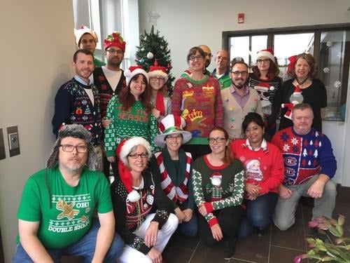 Season’s Greetings  &amp;  Happy New Year to all from Plant Operations - a group photo of people wearing Christmas sweaters.