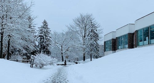 A person walks on a snow-covered path outside South Campus Hall.