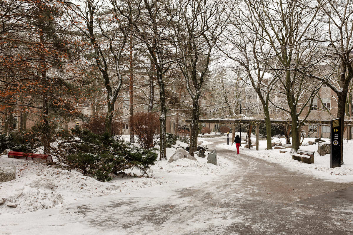 A woman walks through the Peter Russell Rock Garden with snow on the ground.