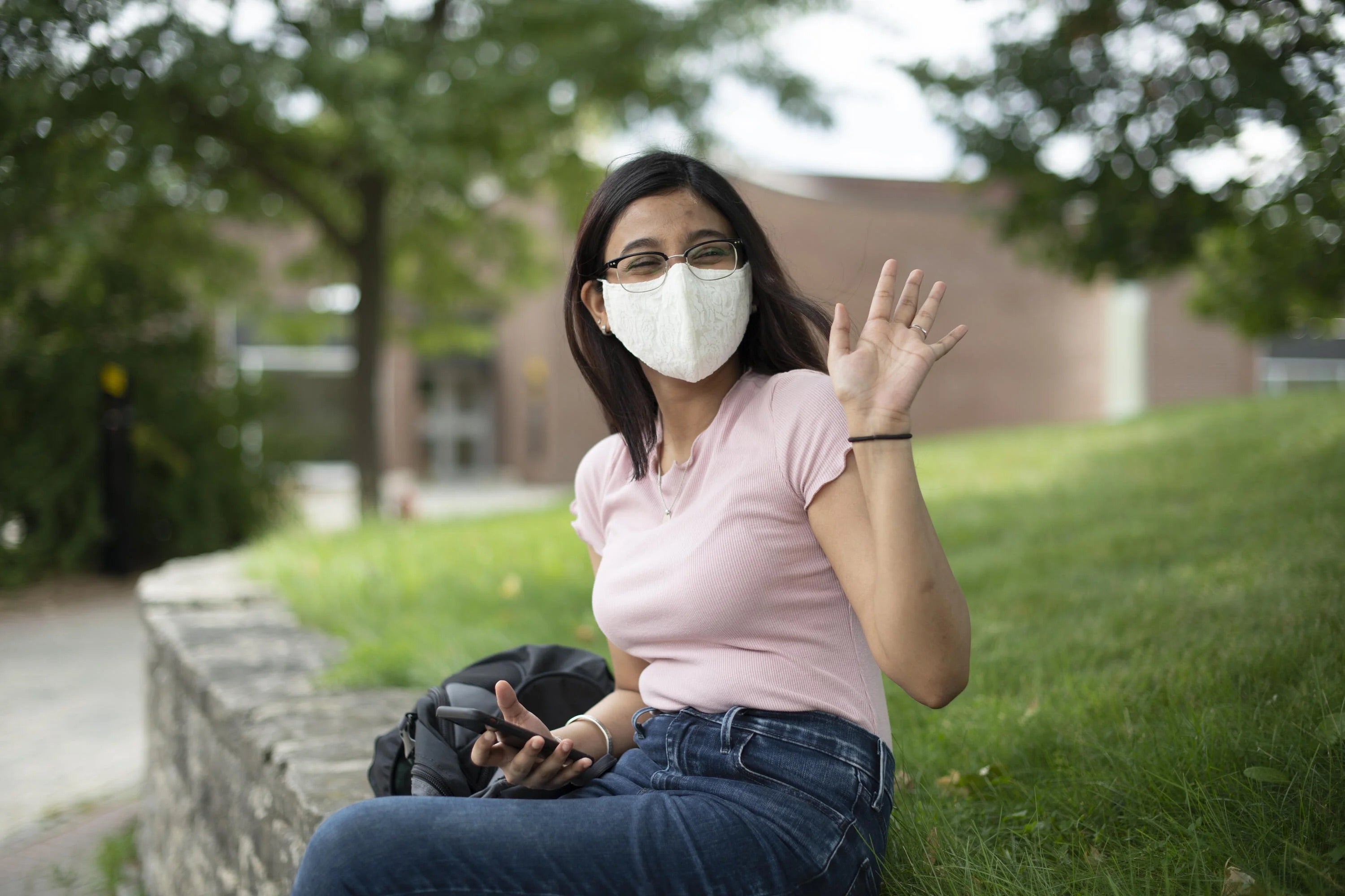 A student wearing a mask waving goodbye.