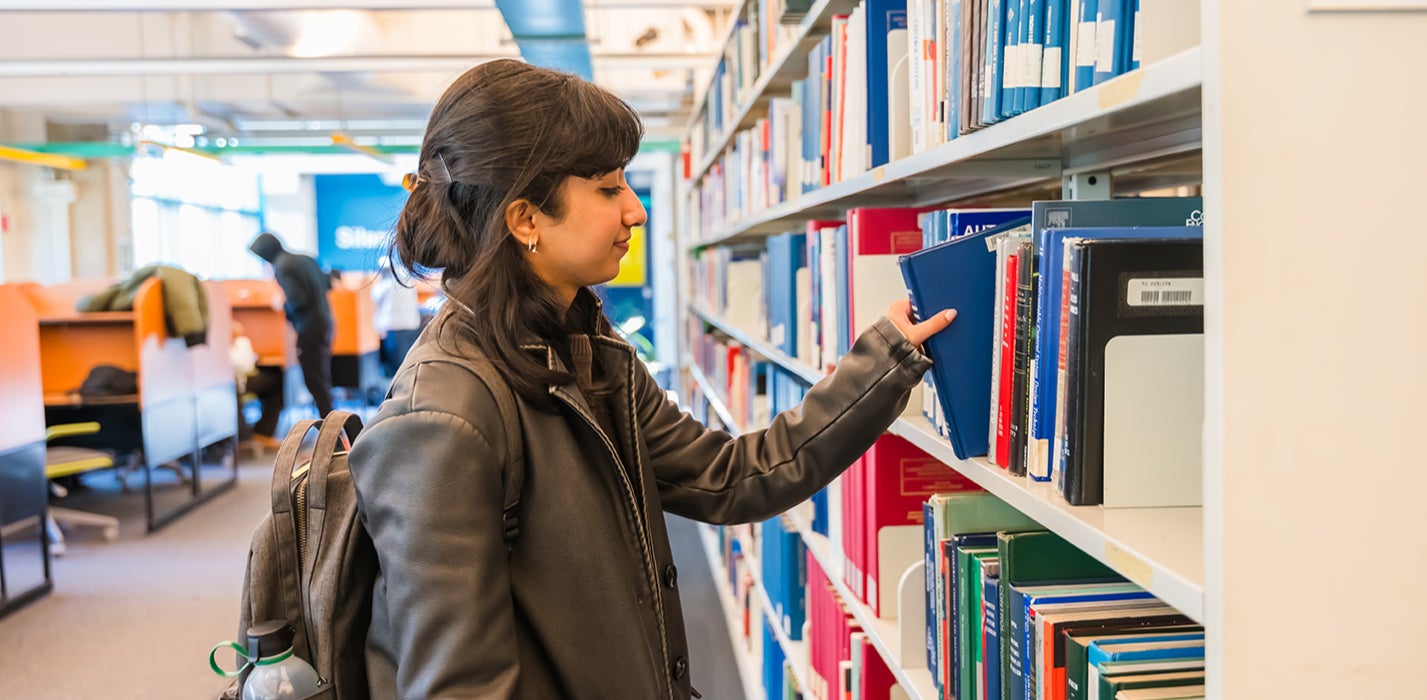 Student choosing a book from a shelf