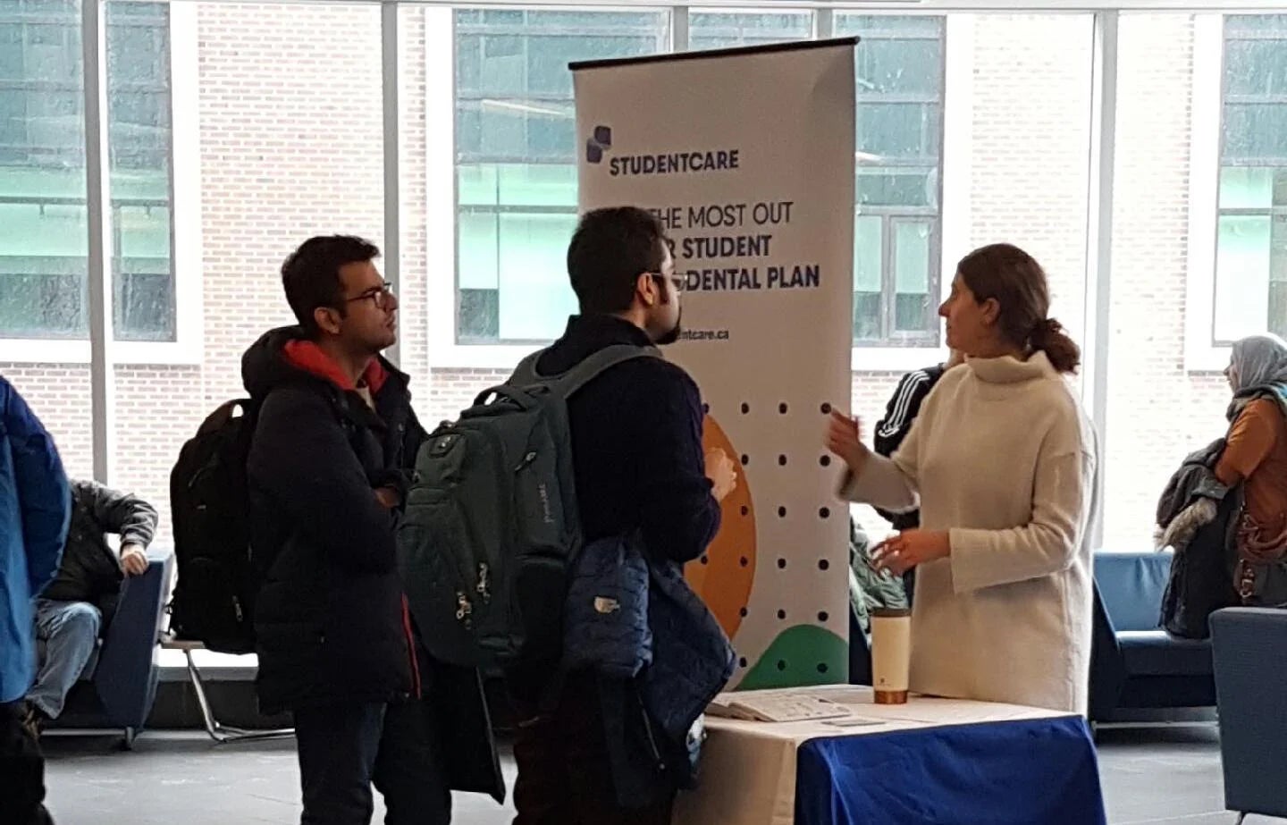 two students speaking a volunteer at a help booth