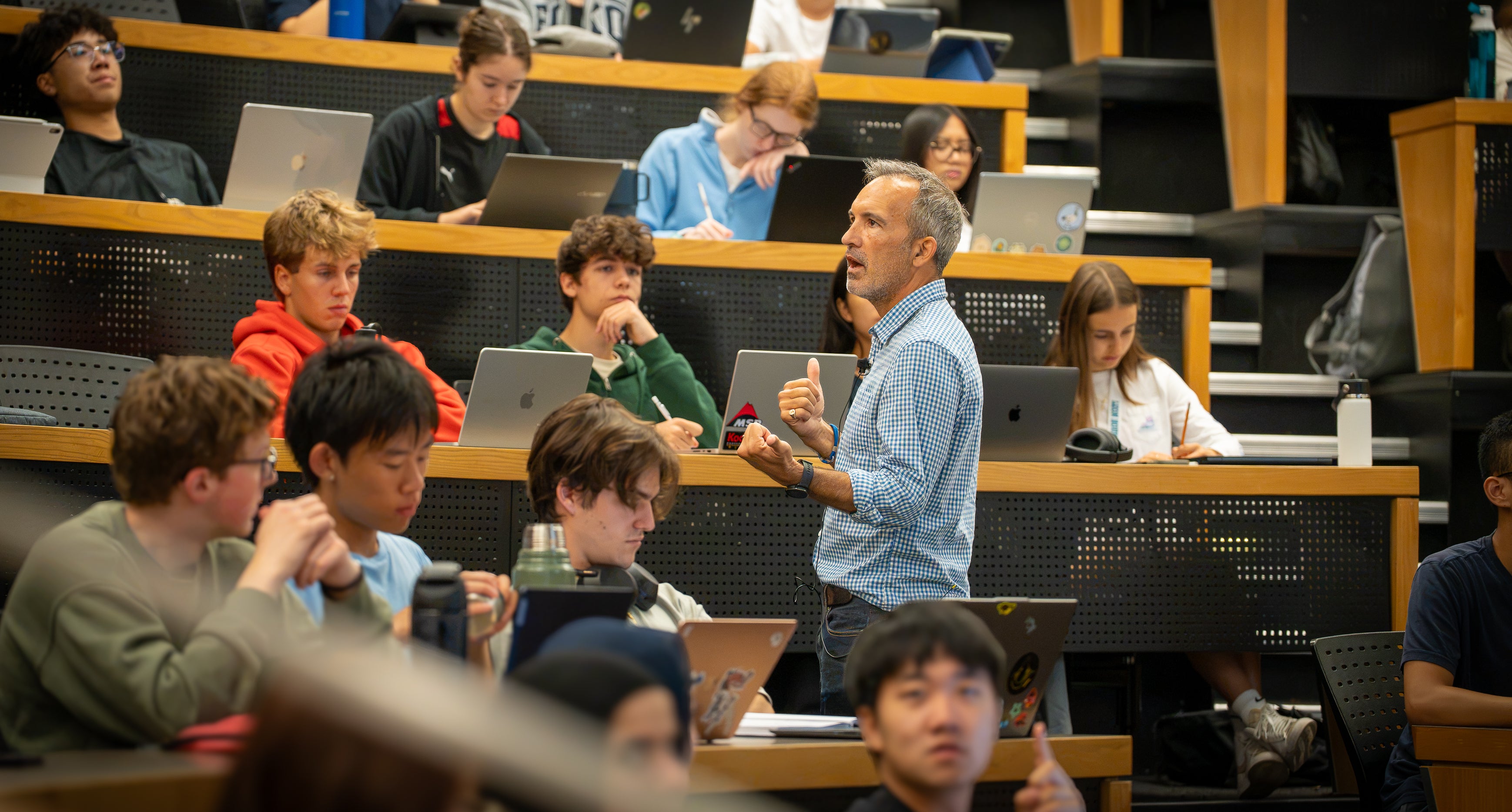 Students participate in a classroom discussion during a lecture in a university lecture hall.