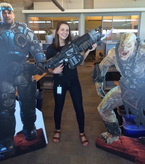 Tina Wilton poses with a prop rifle and Gears of War cutout figures.