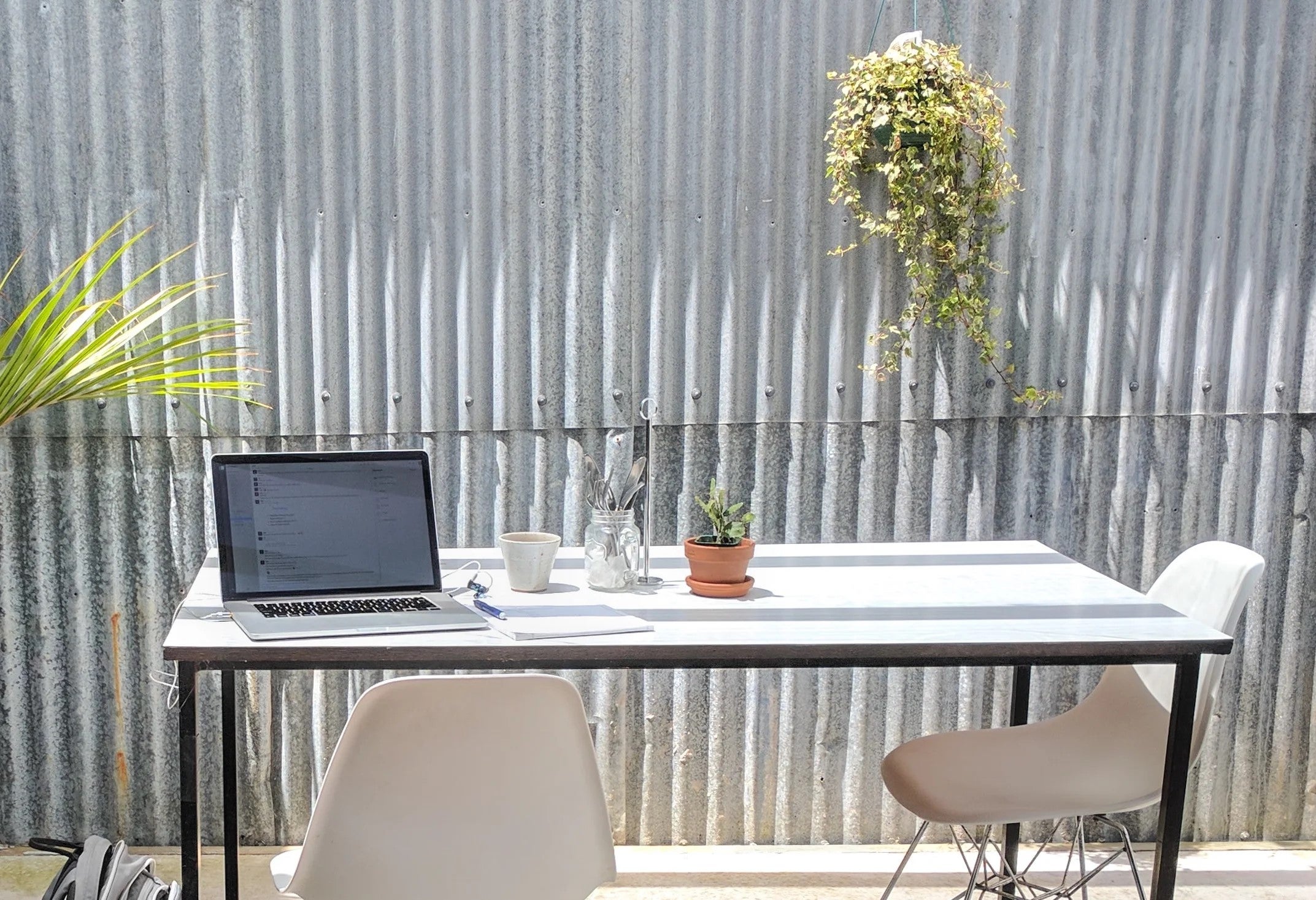 Desk with a lap and plant on it in front of an aluminium sided wall