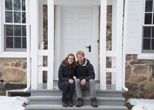 A man and a women sitting at the stairs in front of a house