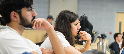 a female student focuses intently in a lecture hall
