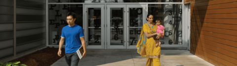 Two students walking outside of a building entrance 