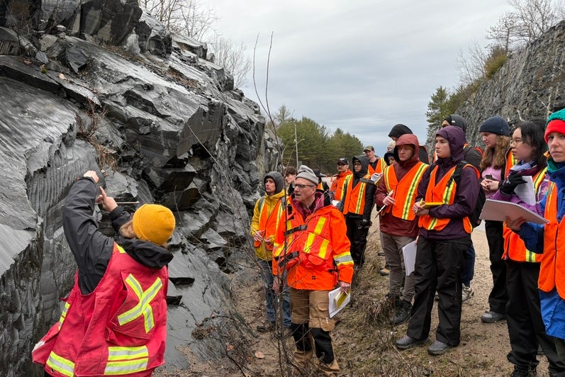 An instructor points out rock formations to a group of students. 