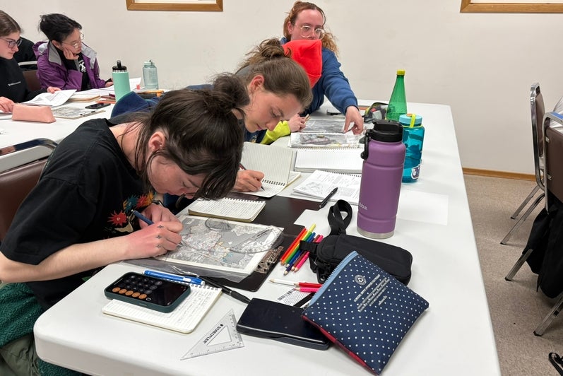 Students at a table working on maps. 