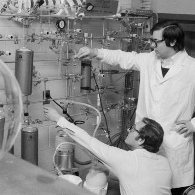 Two men in lab coats using carbon dating equipment. 