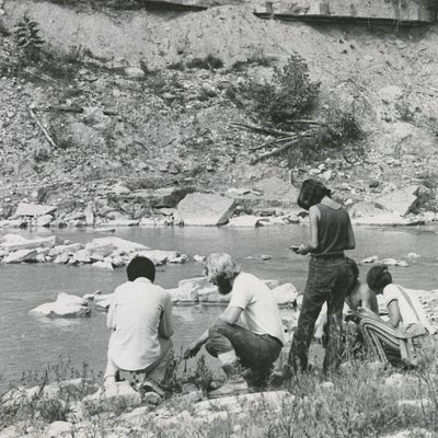 A group of Earth Science students take samples next to a stream. 