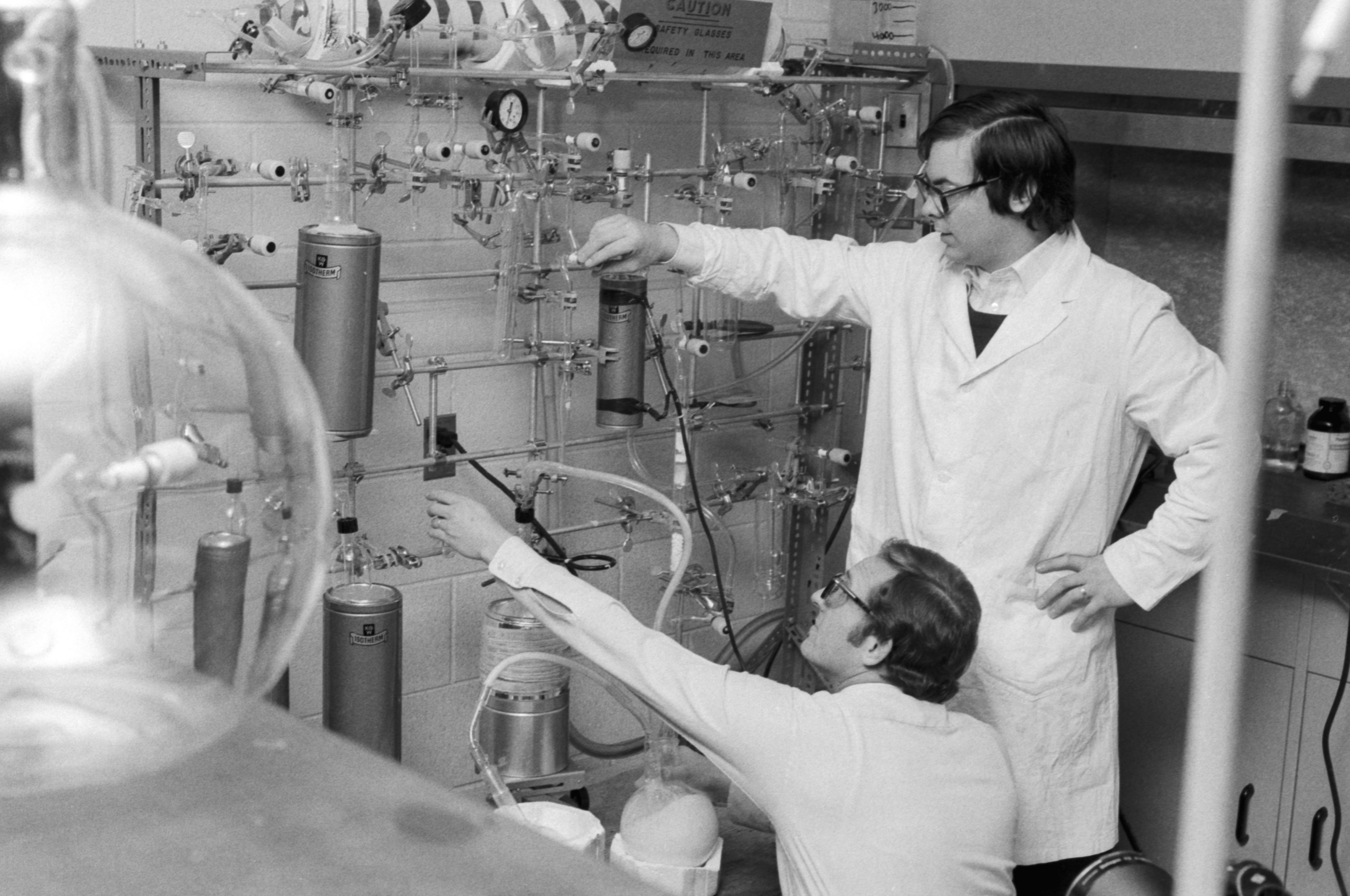 Two men in lab coats using carbon dating equipment. 