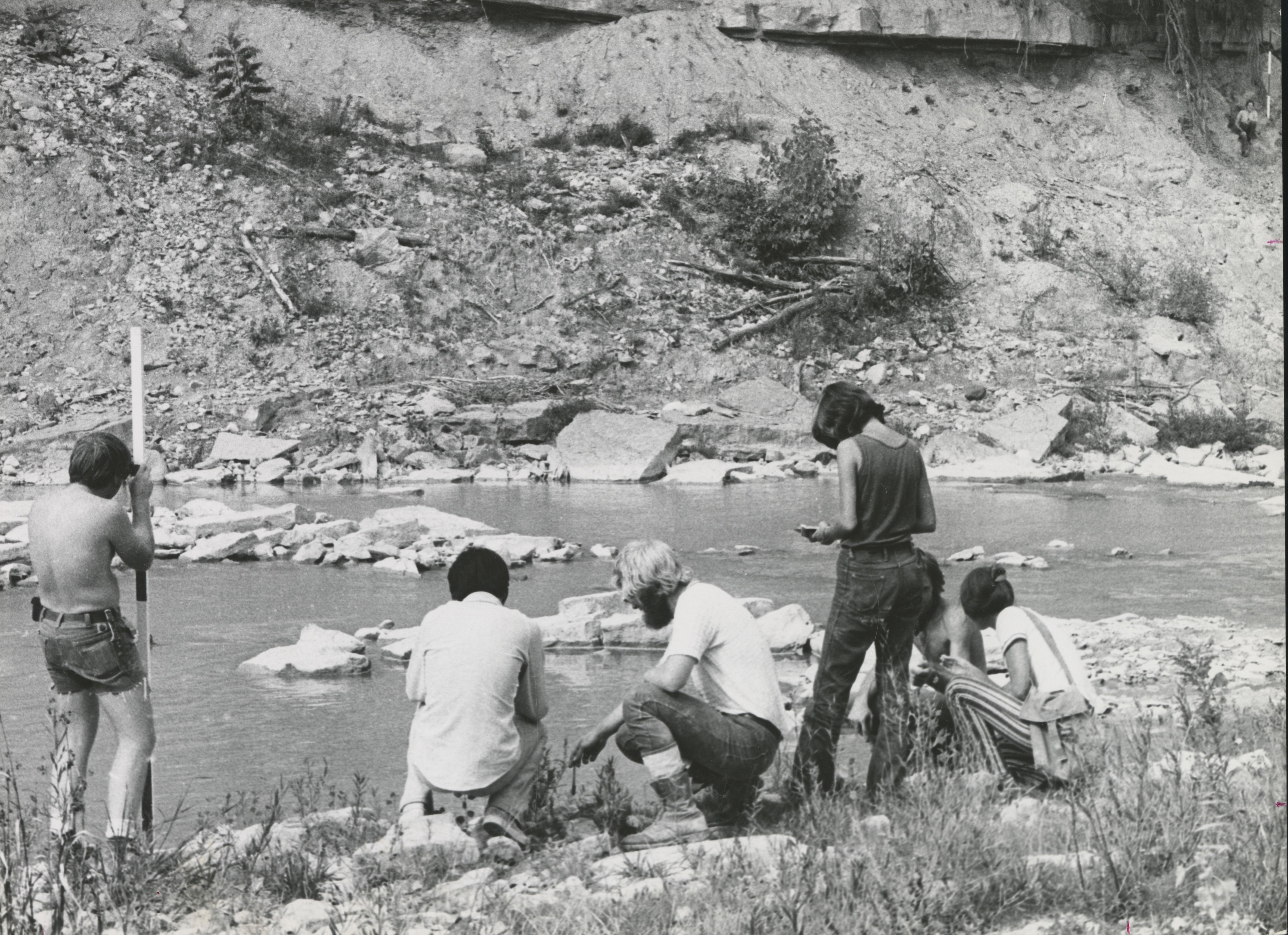 A group of Earth Science students take samples next to a stream. 
