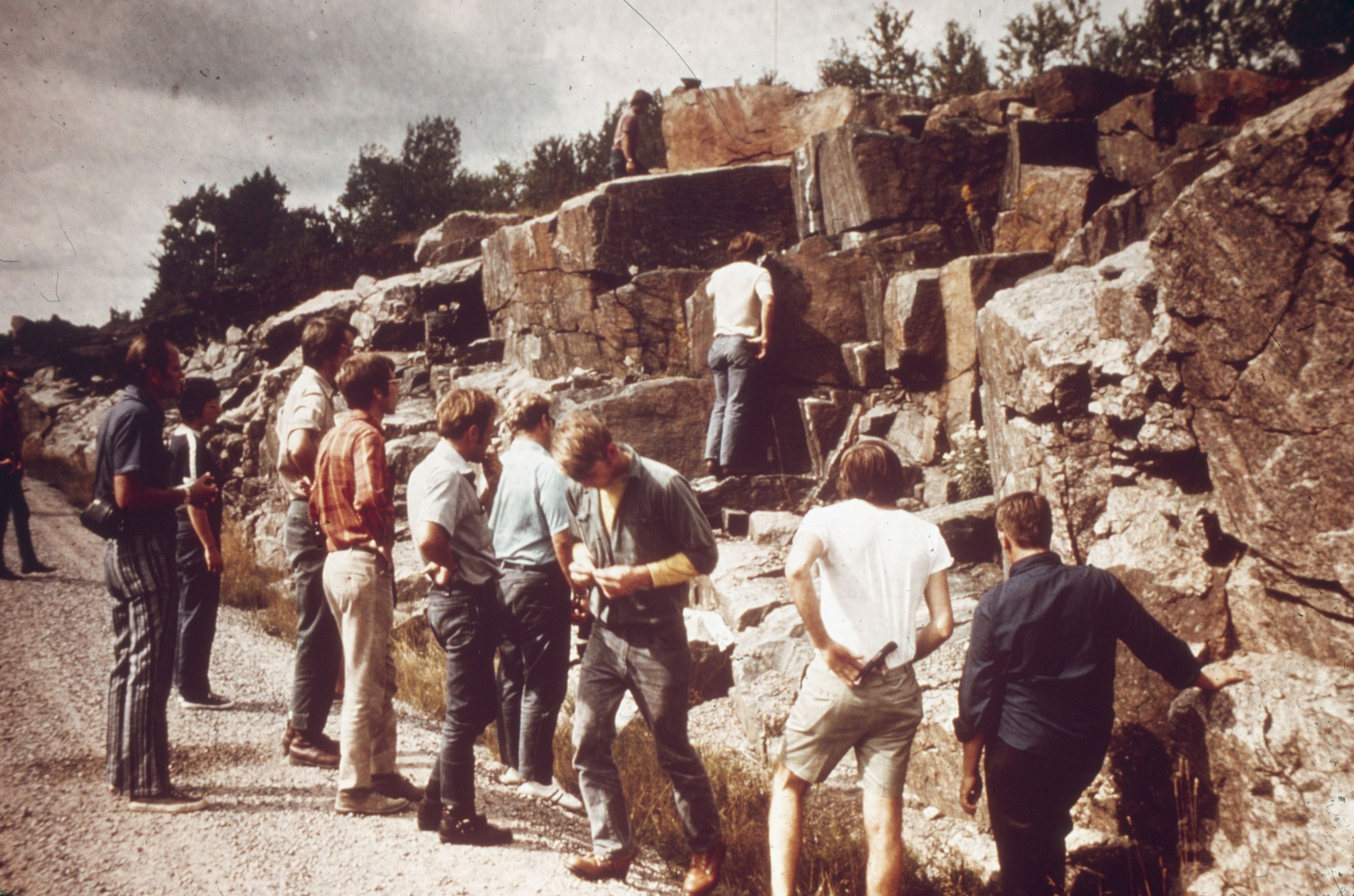 A group of Earth Science students stand next to rock wall. 