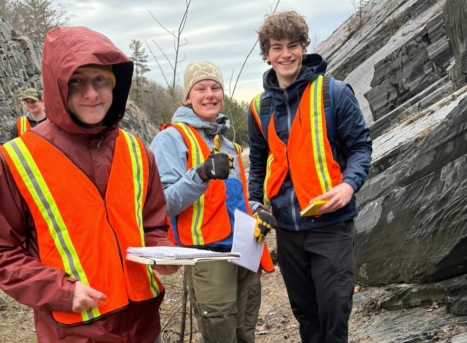 Three students next to a rock formation. 