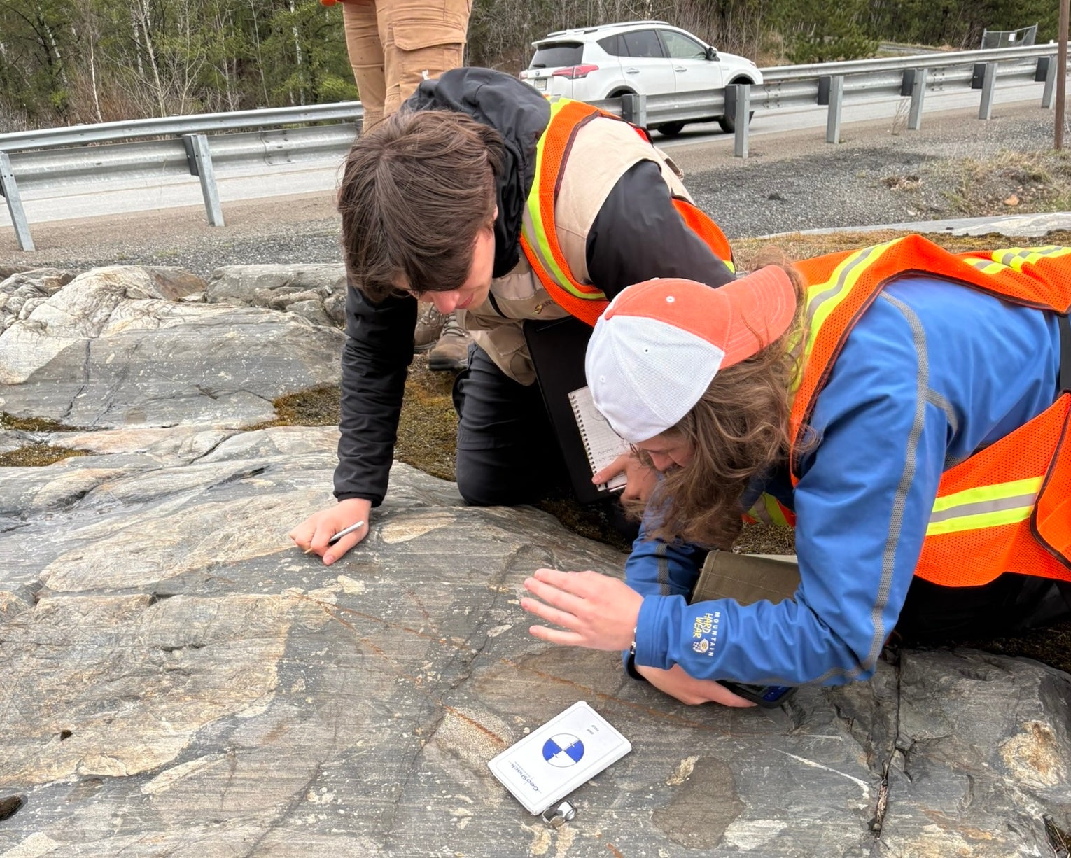 Two students studying a rock in the field. 