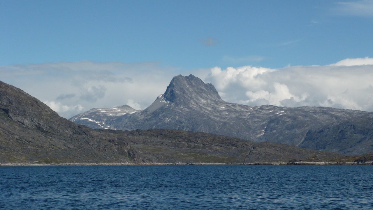 Scenic photo of a mountain in Greenland, with the ocean in the foreground