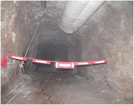 A mining tunnel with caution tape across the entrance.