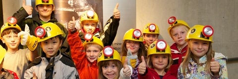 Children with hard hats entering the Cobalt Mine Tunnel.