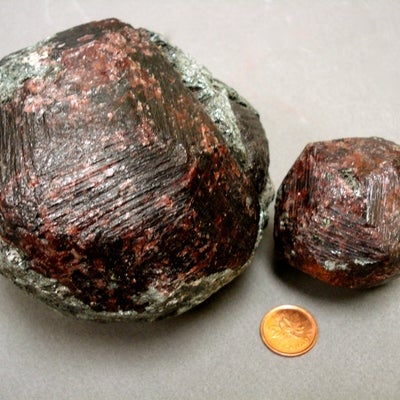 2 pieces of Almandine Garnet next to a penny for size comparison