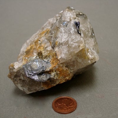 Molybdenite next to a penny for size comparison