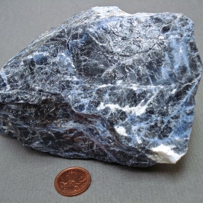 Sodalite next to a penny for size comparison