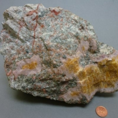 Cancrinite next to a penny for size comparison.