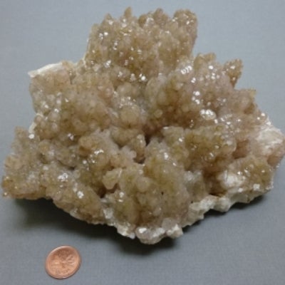 Calcite next to a penny for size comparison.