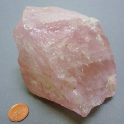 Rose quartz next to a penny for size comparison