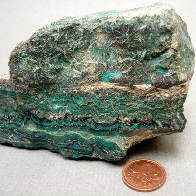 Chrysocolla next to a penny for size comparison