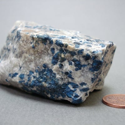 Lazulite next to a penny for size comparison