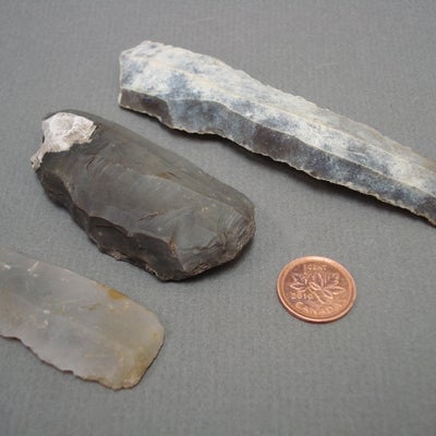 Neolithic Flint Knives next to a penny for size comparison