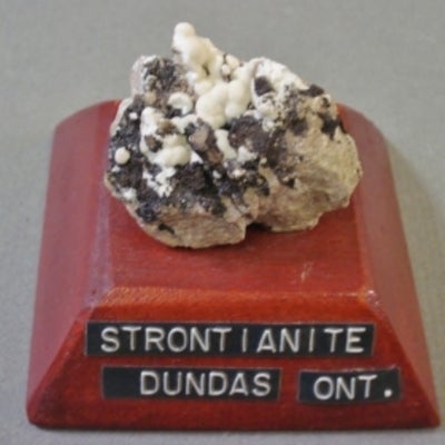 Strontianite mounted on a wood base with a label