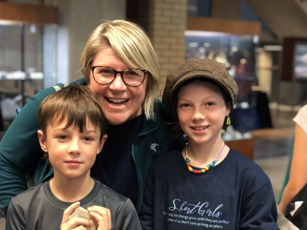 A mom, son and daughter smile together in the museum.