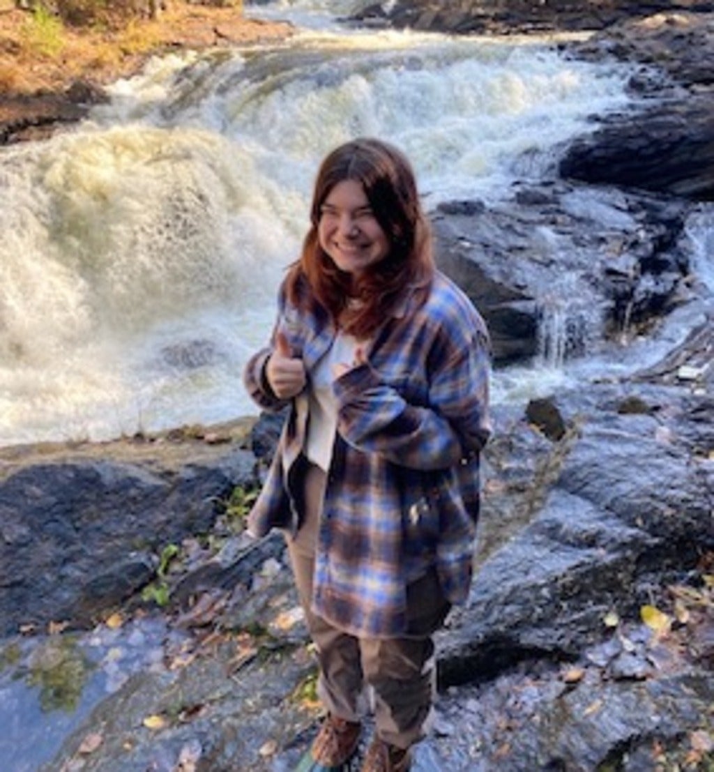 Asia Maheu standing next to a waterfall in Bancroft, ON