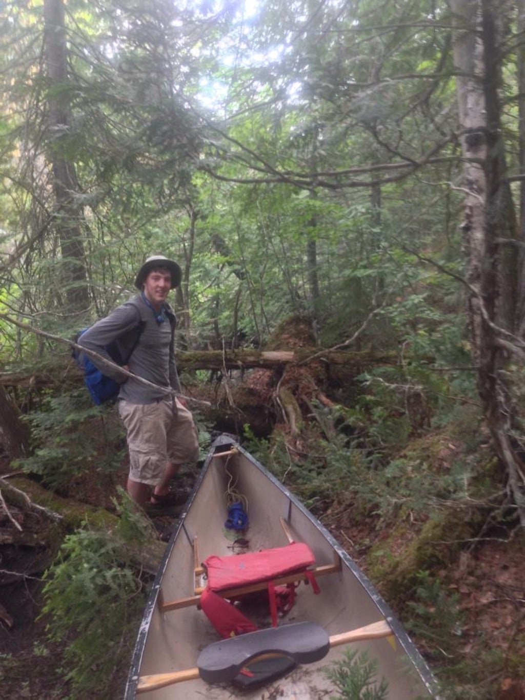 Stephen adventuring through the woods with his canoe