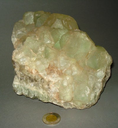 piece of green fluorite mineral next to a toonie for size comparison