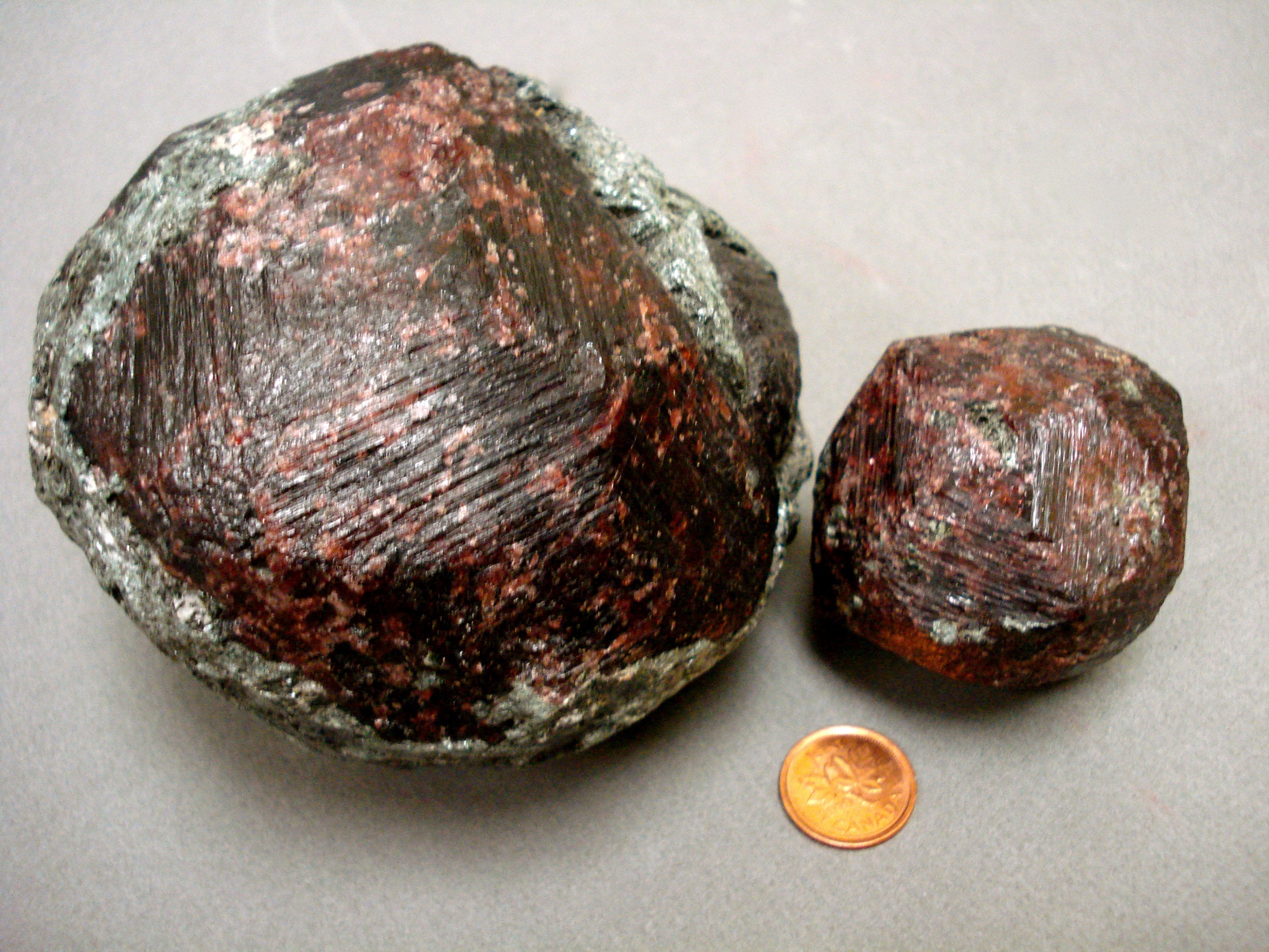 2 pieces of Almandine Garnet next to a penny for size comparison