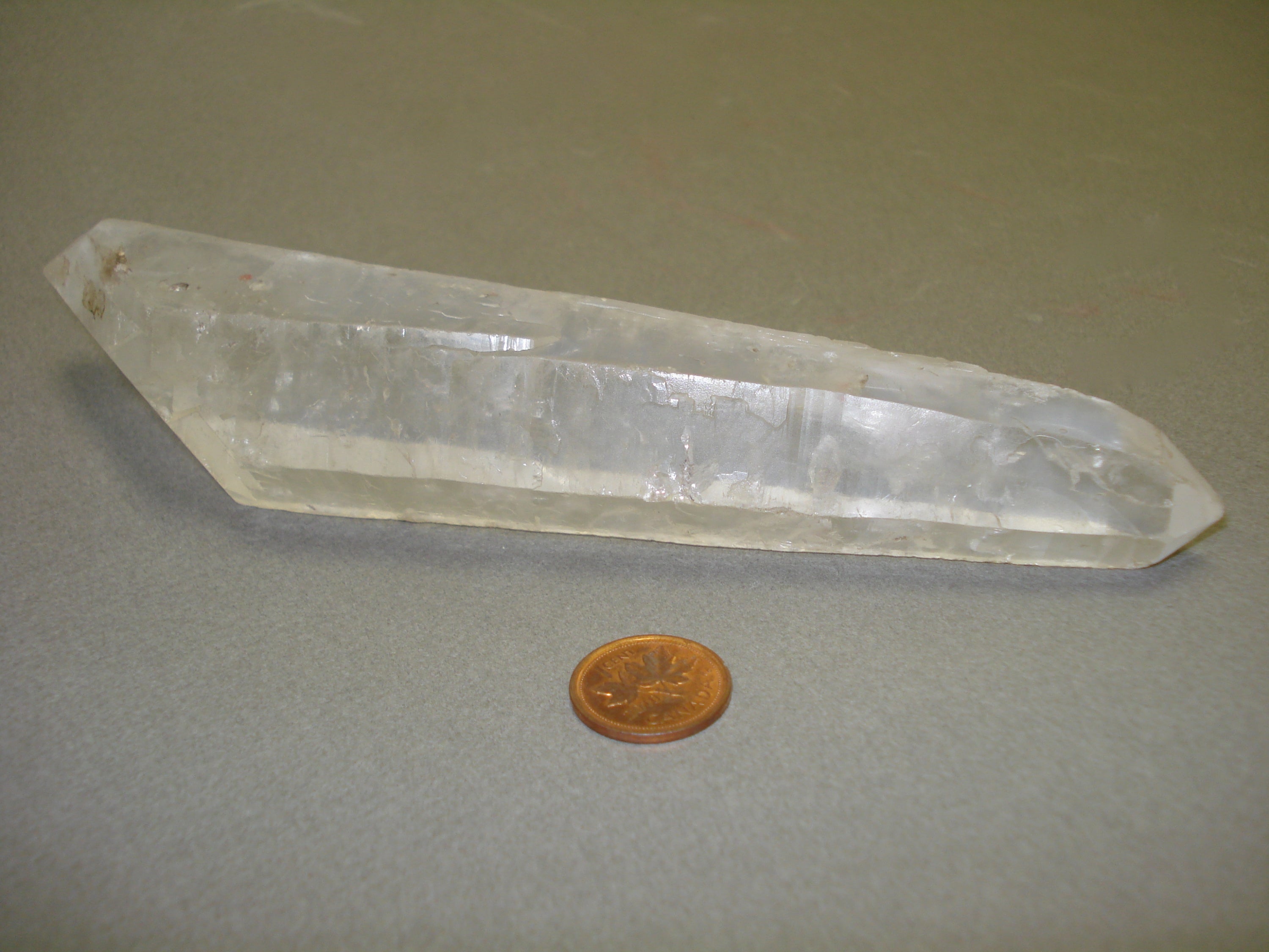 Double-Terminated Quartz Crystal next to a penny for size comparison