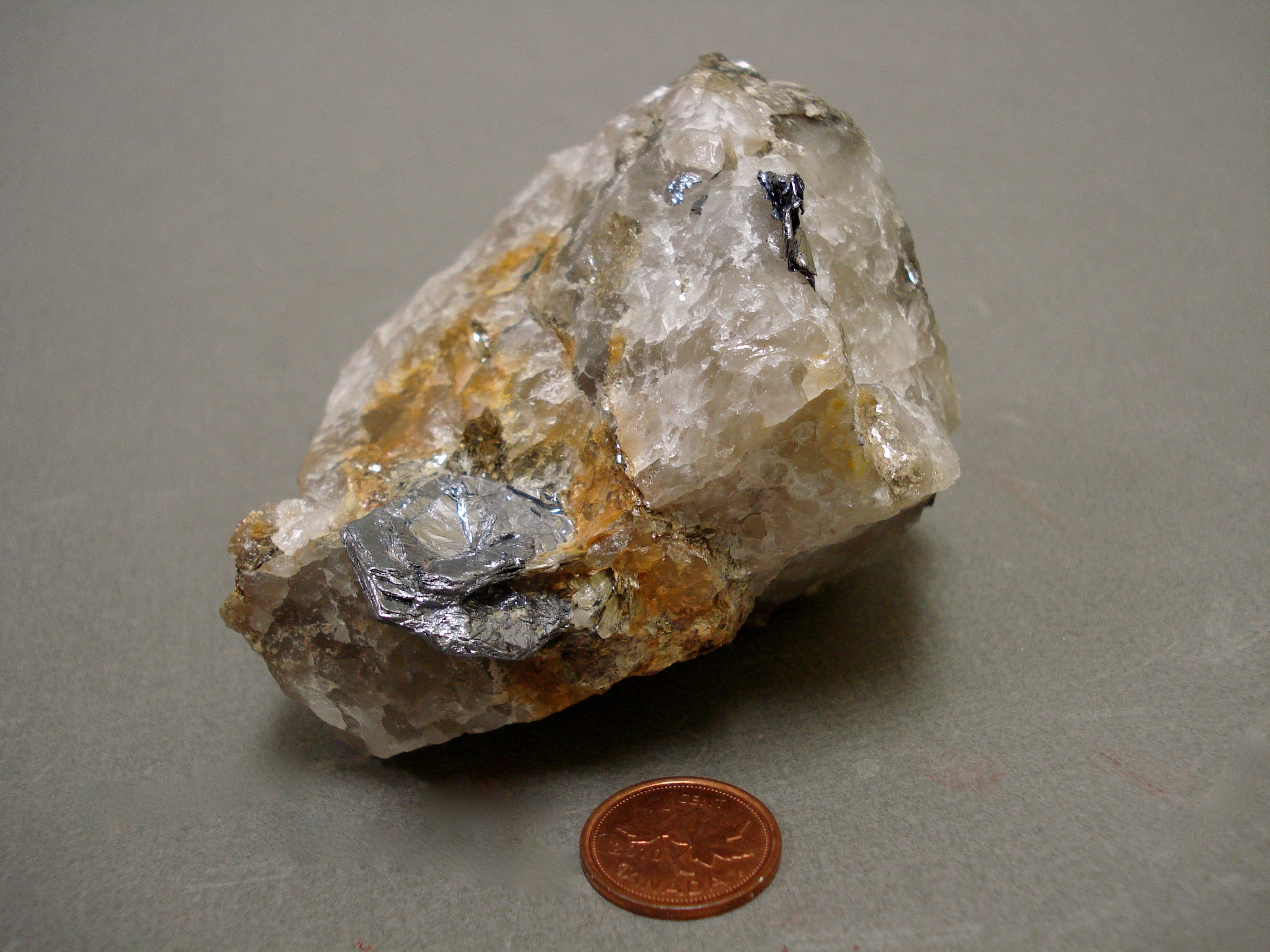 Molybdenite next to a penny for size comparison